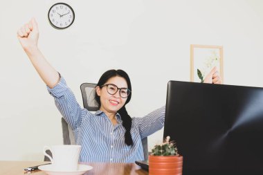 Seçici odak noktası, gülümseyen güzel Asyalı kadın gözlük takıyordu, mavi çizgili gömlek masada oturuyordu, online yaşam tarzı üzerinde çalışıyordu kahveyle evde dinleniyor, dizüstü bilgisayarla çalışıyor, ev konseptinden çalışıyor.