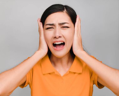 Genç ve güzel Asyalı bir kadın, uzun siyah saçlı, turuncu tişörtlü, huysuz bir ifade sergiliyor, dinlemek istemiyor.