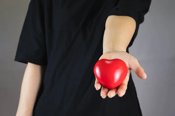 Într Tricou Negru Întins Mâna Ținând Inima Roșie Din Plastic — Fotografie, imagine de stoc