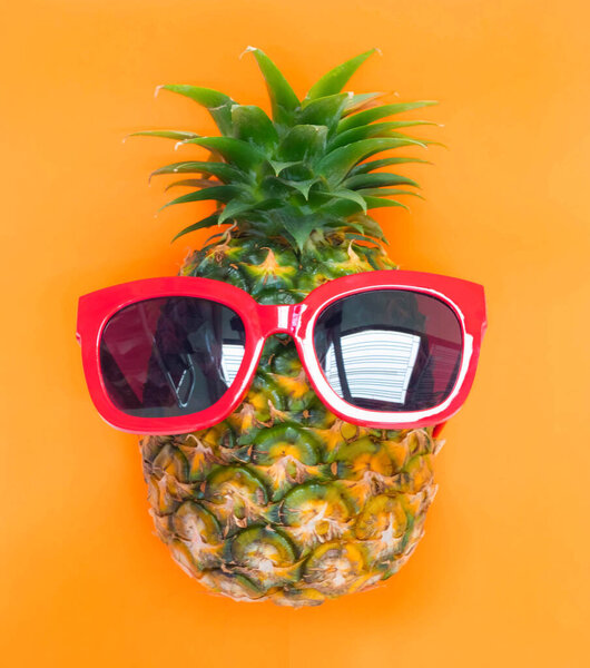 Beach,Funny pineapple in a red sunglasses and hat on the sand against sea and sky.Tropical summer vacation concept. Sunny day on the beach,Selective focus yellow and blue sea