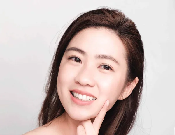 きれいな肌と明るい肌を持つ若い美しいアジアの女性 化粧品の美しさのコンセプト 頬に手のタッチ 灰色の背景に隔離された笑顔とフレンドリーな顔 — ストック写真