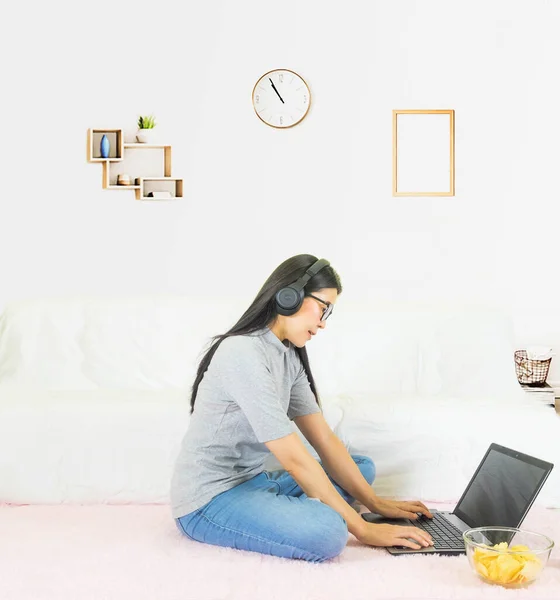 soft selective focus Young beautiful asian woman wore gray t shirt and jean,sitting on pink carpet in living room ,work online lifestyle,relax at home with coffee mug,home working laptop,work from home