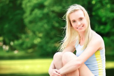 Çok gülümseyen sarışın parkta oturan