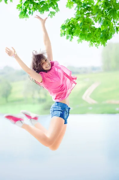 Glückliches Mädchen springt gegen den See — Stockfoto