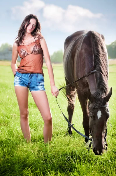 Jovem menina bonita andando com um cavalo no campo — Fotografia de Stock