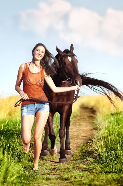 Όμορφη κοπέλα περπάτημα με ένα άλογο στο χωράφι — Φωτογραφία Αρχείου