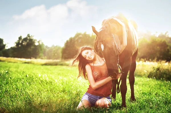 Junges schönes Mädchen, das mit einem Pferd auf dem Feld geht — Stockfoto