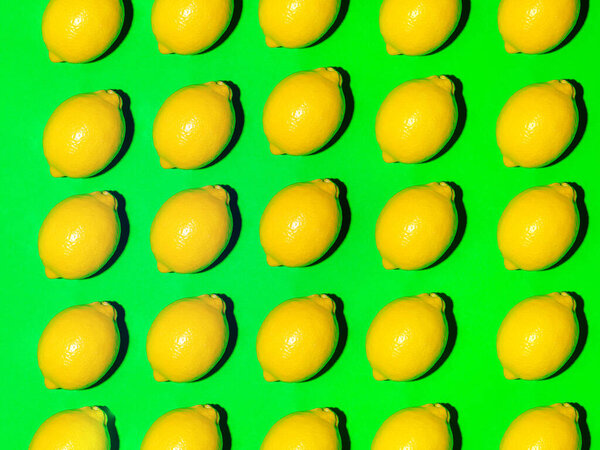 Colorful fruit pattern of fresh lemons on a green background. Top view
