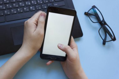 Adam dizüstü bilgisayarda çalışıyor ve elinde düz bir şekilde bir telefon tutuyor. Evden çalışırken konsantrasyon sorunu. Evde bilgisayarla çalışırken dikkati dağılan adam..