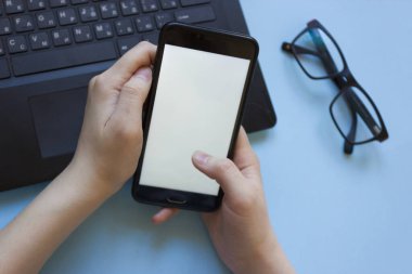 Adam dizüstü bilgisayarda çalışıyor ve elinde düz bir şekilde bir telefon tutuyor. Evden çalışırken konsantrasyon sorunu. Evde bilgisayarla çalışırken dikkati dağılan adam..