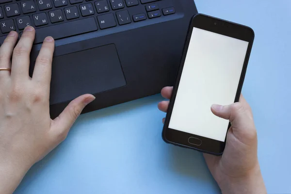 Adam dizüstü bilgisayarda çalışıyor ve elinde düz bir şekilde bir telefon tutuyor. Evden çalışırken konsantrasyon sorunu. Evde bilgisayarla çalışırken dikkati dağılan adam..