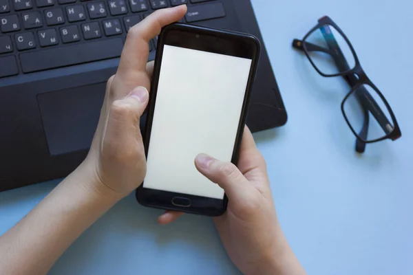 Adam dizüstü bilgisayarda çalışıyor ve elinde düz bir şekilde bir telefon tutuyor. Evden çalışırken konsantrasyon sorunu. Evde bilgisayarla çalışırken dikkati dağılan adam..