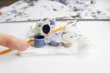 Rakamlara göre resim. Tuvale resim çiziyorum. Numaralı boya kutuları. Yaratıcı hobi. Seçici odaklanma. Kapat. Akrilik boyalarla numaralar çizerek. Karantinaya alınmış eğlence..