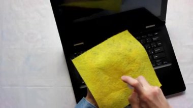 Dizüstü bilgisayarın klavyesinde oturan biri klavyeyi antiseptik bir bezle siler. Yüksek kaliteli görüntüler 