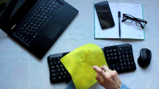 노트북 컴퓨터의 키보드에 앉아 있는 사람은 방부제 천으로 키보드와 마우스를 닦습니다. 고화질 장면 — 비디오