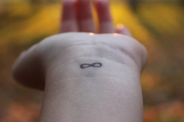 closeup of the arm with an infinity symbol tattooed in his wrist. infinity sign on the hand. endless love concept