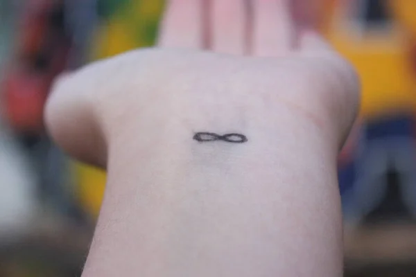 closeup of the arm with an infinity symbol tattooed in his wrist. infinity sign on the hand. endless love concept