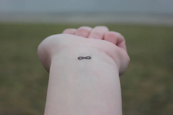 closeup of the arm with an infinity symbol tattooed in his wrist. infinity sign on the hand. endless love concept