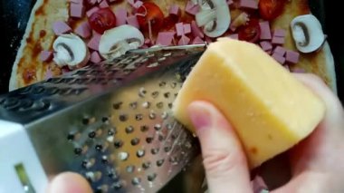 Yavaş çekim videosu. Adam pizzanın üstünde peynir rendeliyor. 4k video