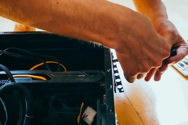 Senior male tech works in hardware repair facility.guy is assembling a computer.