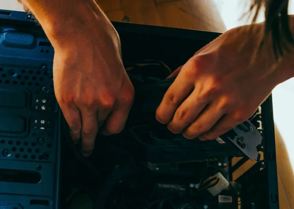 Senior male tech works in hardware repair facility.guy is assembling a computer.