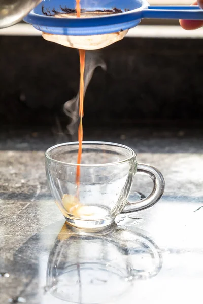Şeffaf cam bir fincana buharlı masala çayı dökülüyor.