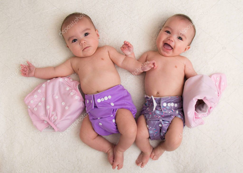 Baby twins girls with cloth diaper on a bed