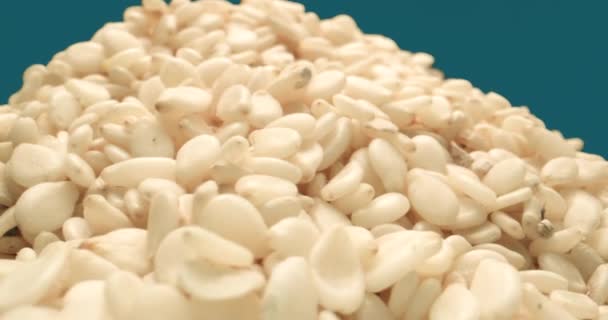 Ekstremalne makro ujęcie nasion sezamu obracających się na niebieskim tle — Wideo stockowe
