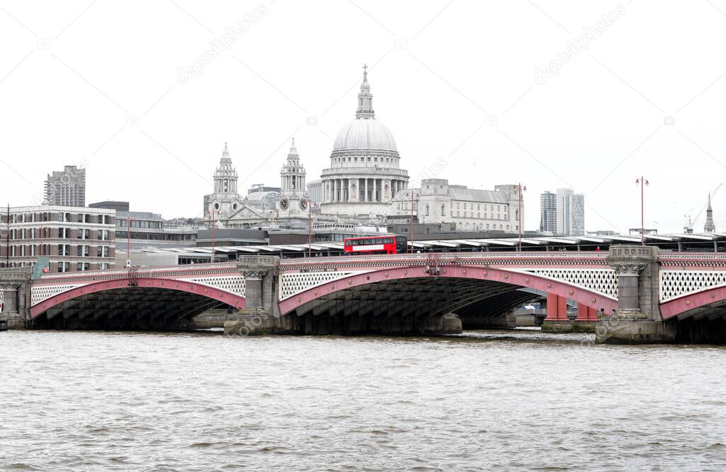 Iconic Red British Bus on Blackfriars Bridge with St Paul`s Cathedral and London Skyline in the background, UK