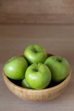 Masadaki tahta kasede yeşil elmalar.