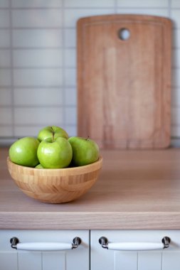 Mutfak masası manzaralı yeşil elmalı ahşap kase arka planda kesim tahtası.