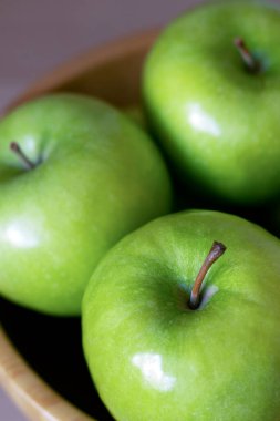 Tahta bir kasede üç yeşil elma. Yaklaş.