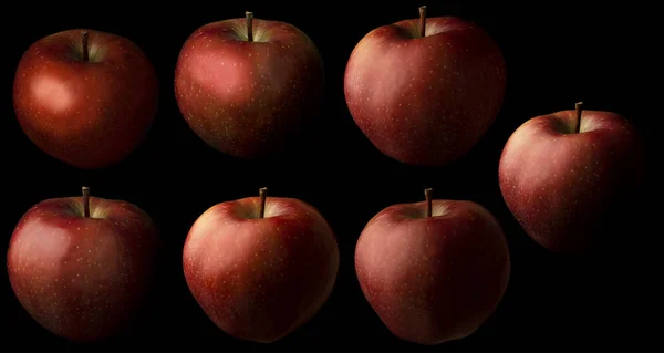 seven red fresh apples on a black background