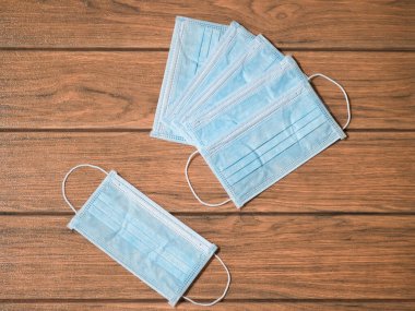 Kulaklıklı tek kullanımlık cerrahi maskeler ve yakın plan bir masa tahtasında bir sürü maske.