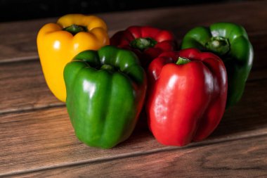 Tahtada farklı renkte altı büyük taze dolma biber.