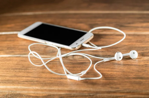 Ein Smartphone Mit Weißen Kabelgebundenen Kopfhörern Auf Einem Holztisch — Stockfoto