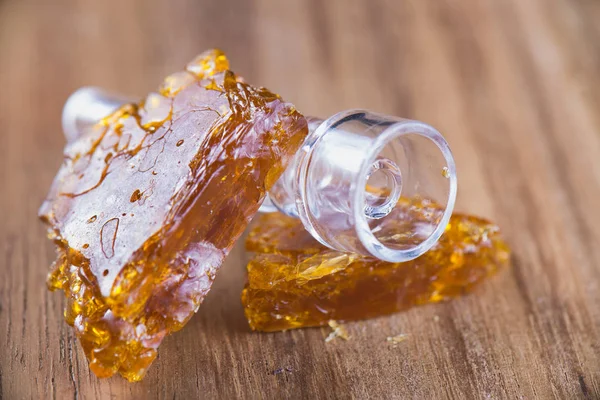 Piececs of cannabis oil concentrate aka shatter over wood backgr — Stock Photo, Image