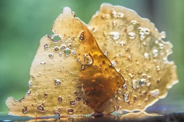 Pieces of cannabis oil concentrate aka shatter against green — Stock Photo, Image