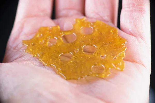 Mão segurando pequeno pedaço de extração de óleo de cannabis concentrado — Fotografia de Stock