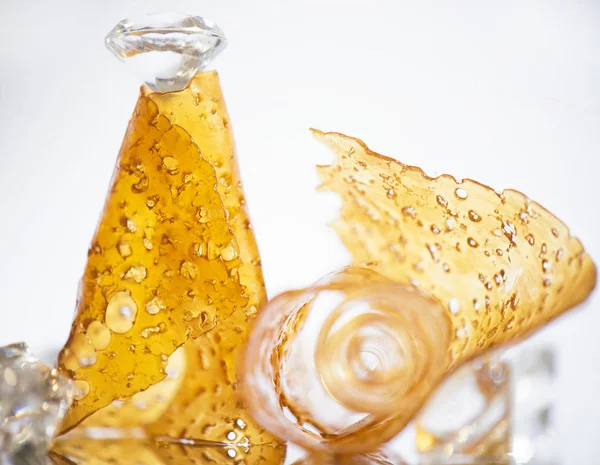 Pieces of cannabis oil concentrate aka shatter isolated against — Stock Photo, Image