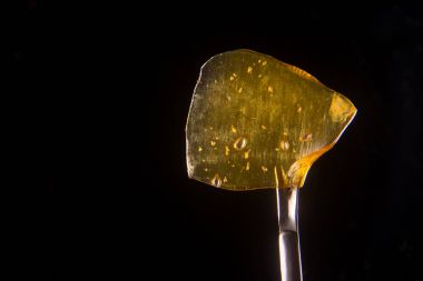 Cannabis oil concentrate aka shatter held on a dabbing tool over clipart