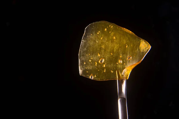 Cannabis oil concentrate aka shatter held on a dabbing tool over — Stock Photo, Image