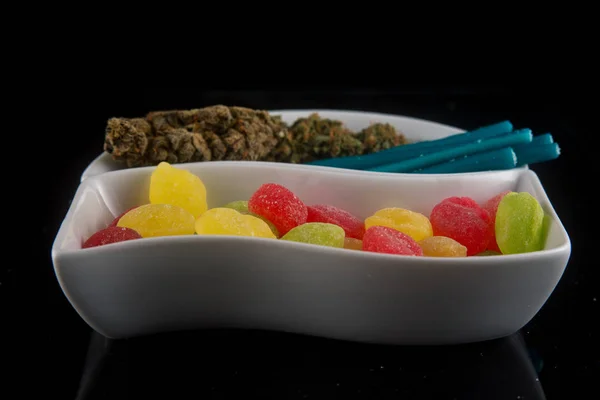 Caramelos infundidos de cannabis en diferentes colores y marihuana seca — Foto de Stock