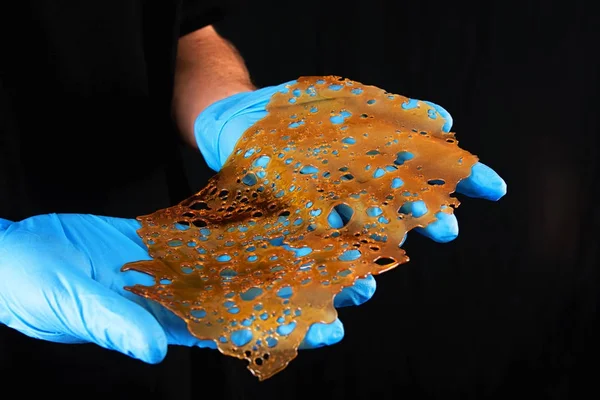 Hand holding a slab of concentrated cannabis oil extraction aka — Stock Photo, Image