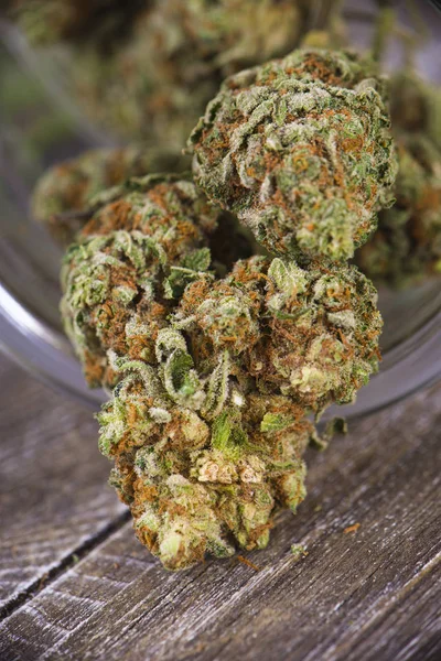 Cannabis buds (scout master strain) on glass jar over wood backg — Stock Photo, Image