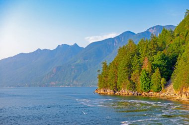 Vancouver At Nalı Koyu 'ndaki Georgia Boğazı manzarası ve ufuktaki dağlar, BC, Kanada' da gün batımında çekildi.