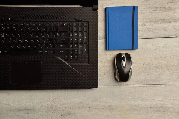 Laptop, notebook and mouse lie on a wooden table