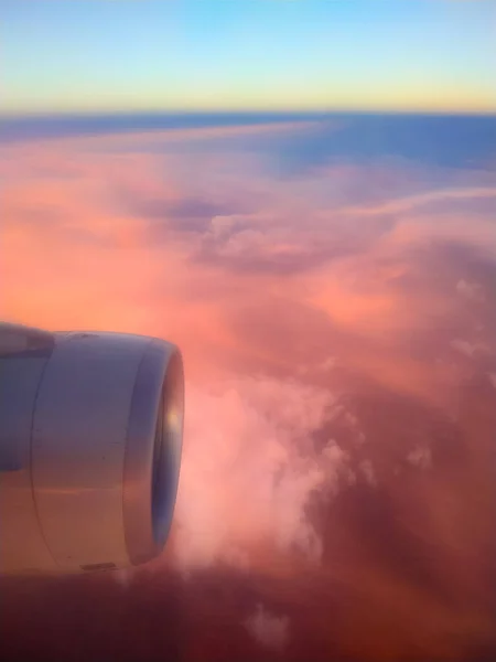 Vertical photography of red clouds on sunset sky made through window of airplane. Selective focus. Beauty in nature theme.