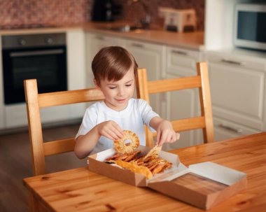 Çocuk kurutulmuş ananas halkalarından oluşan bir kutu çıkardı.