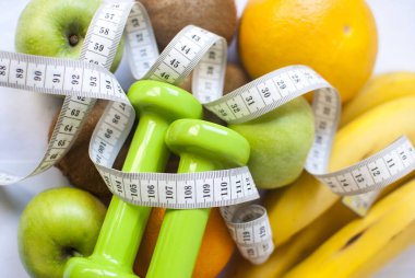 Meyve arka planında dambıllar ve metre